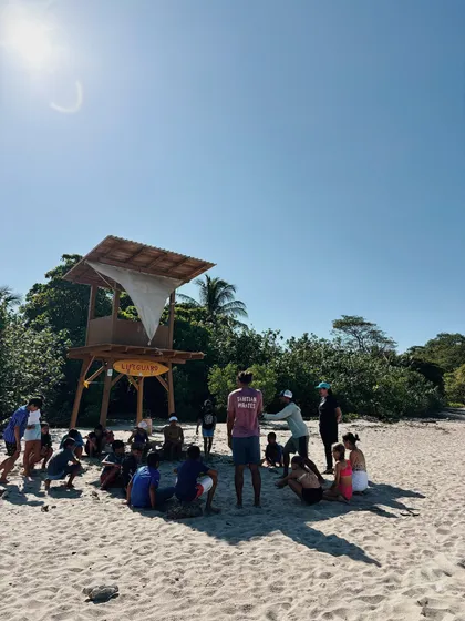 Group sitting on the sand next to a lifeguard tower